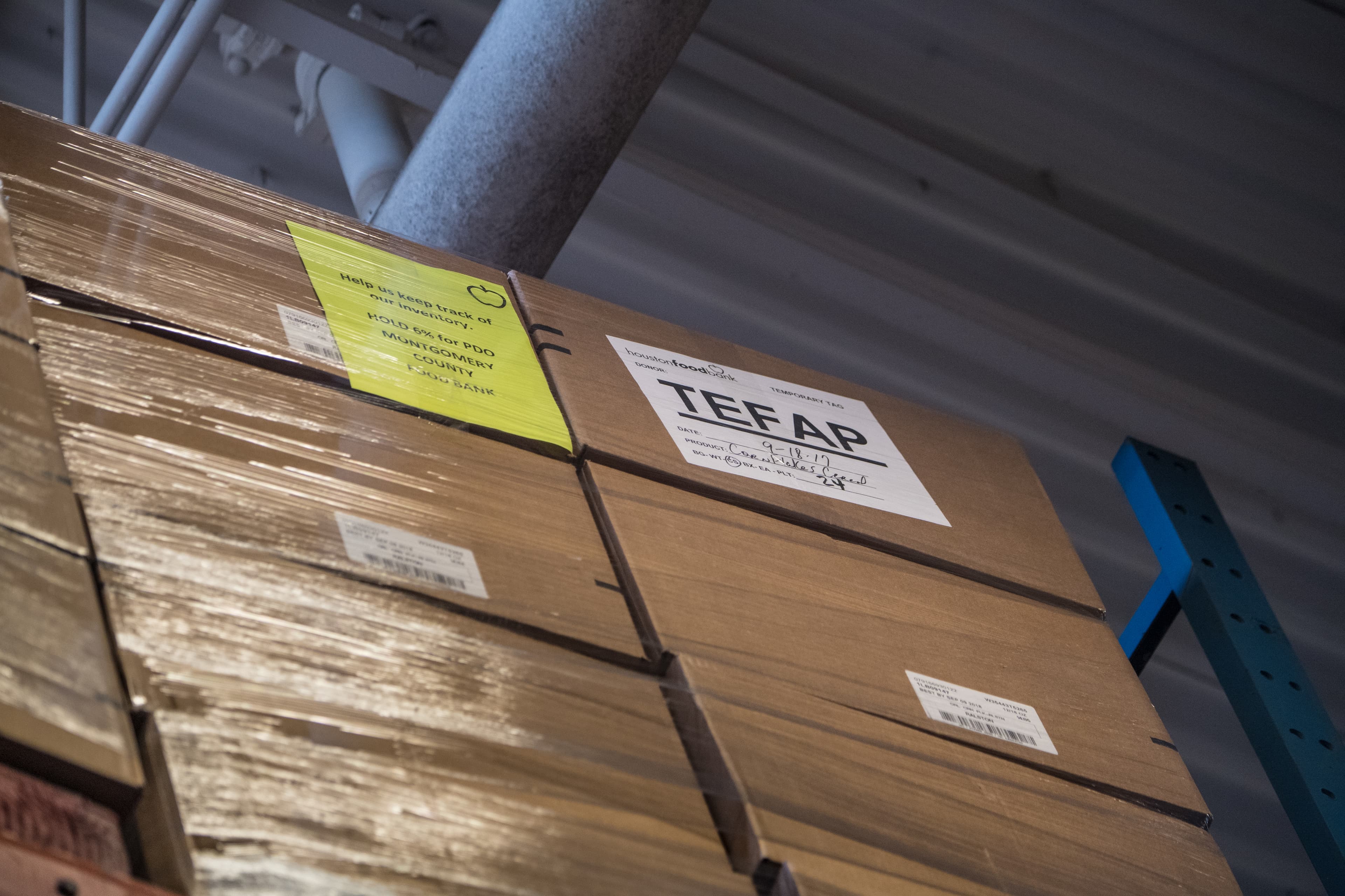 Tall warehouse shelves stacked with boxed inventory and palletized goods