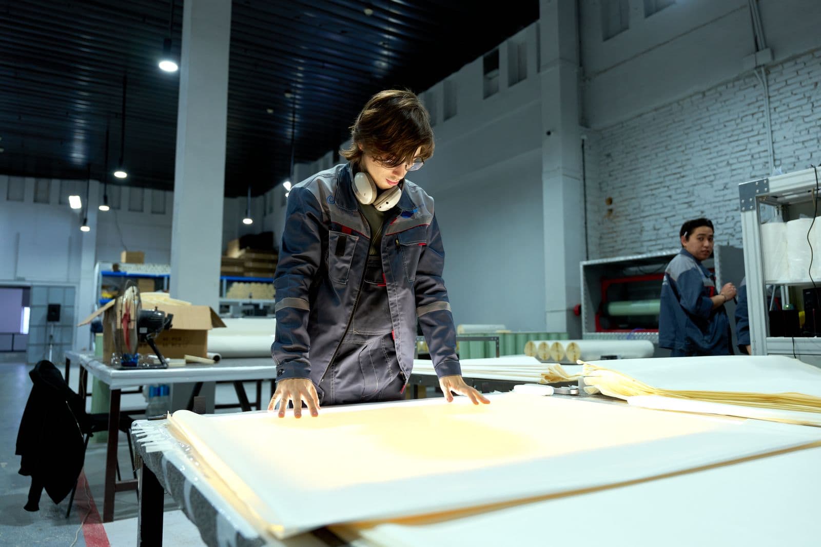 Factory worker inspecting production material under work lights