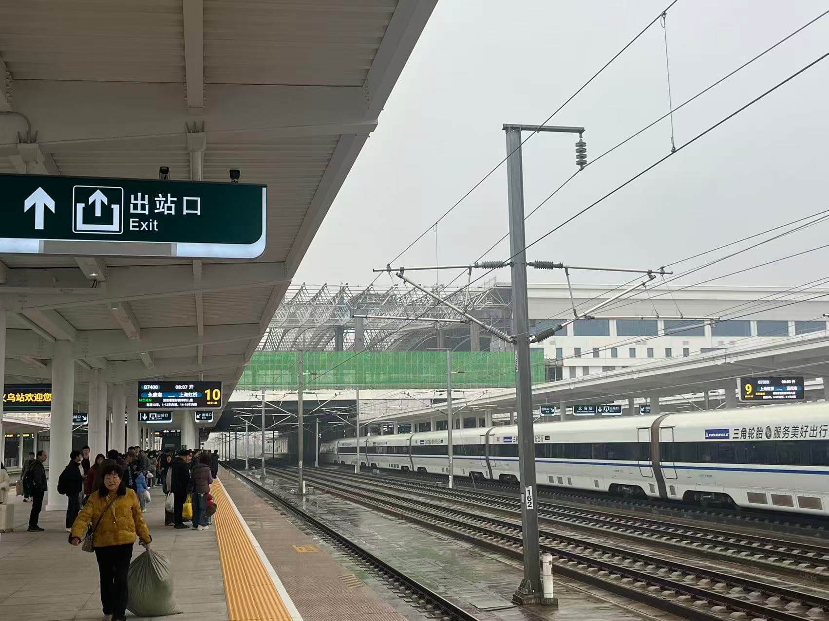 Passengers and high-speed trains on a platform at Yiwu Railway Station